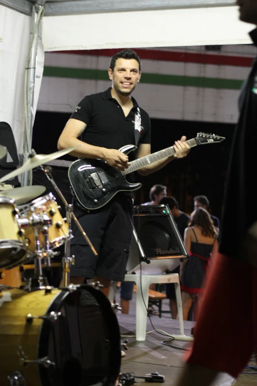 a man standing by a stage holding a guitar