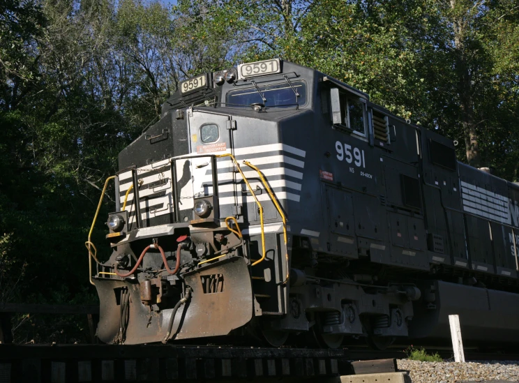 an empty locomotive traveling through the woods on tracks