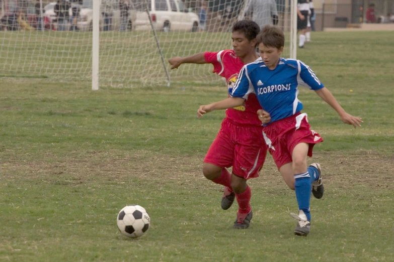 two s are playing soccer on a field