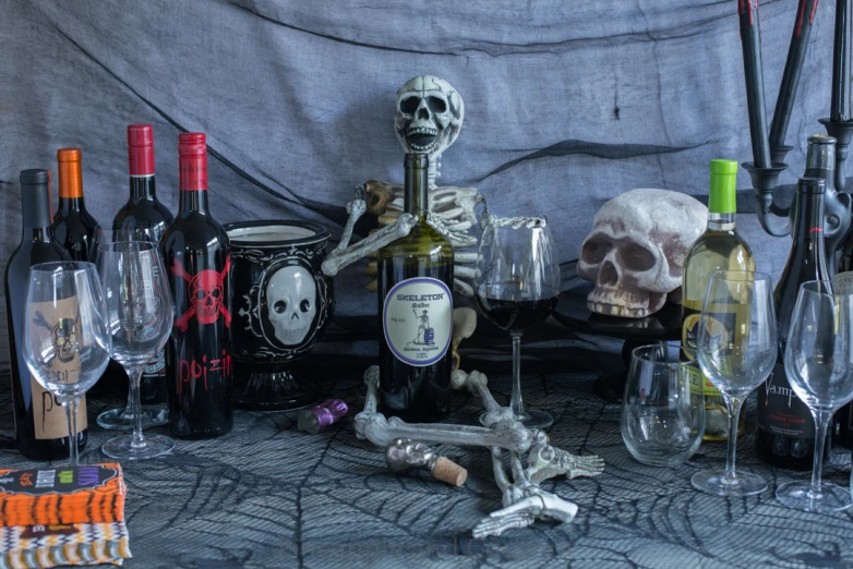 an arrangement of wine glasses and skeletons sitting on a tablecloth