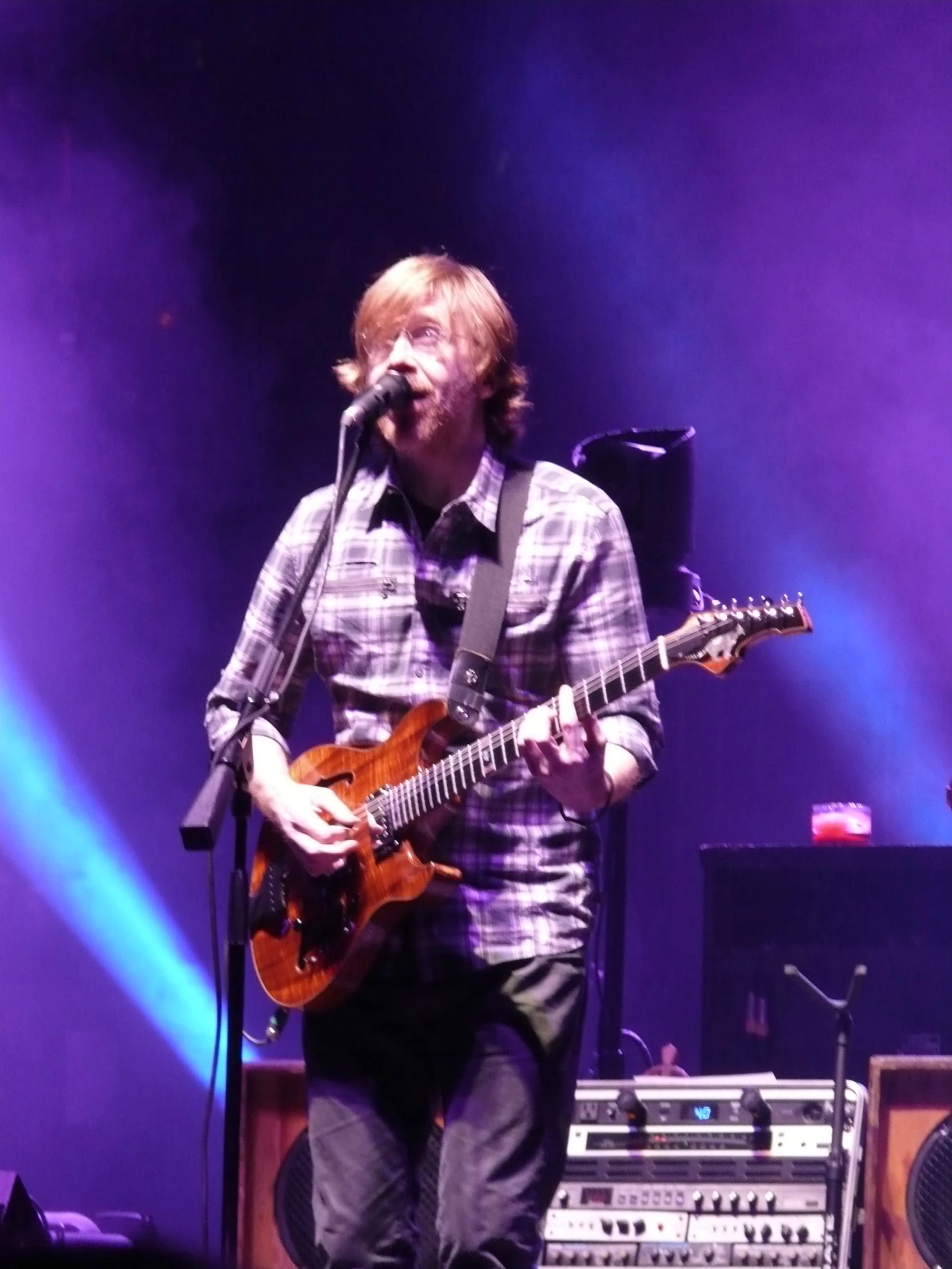 man playing guitar while singing on stage