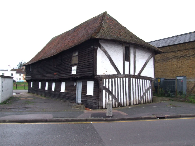 a large wooden building with a gable roof next to a road