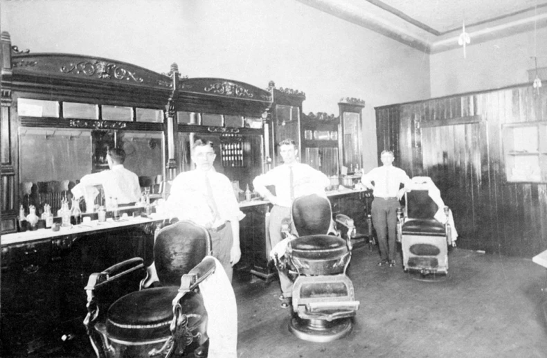 black and white pograph of several men working in a barber shop