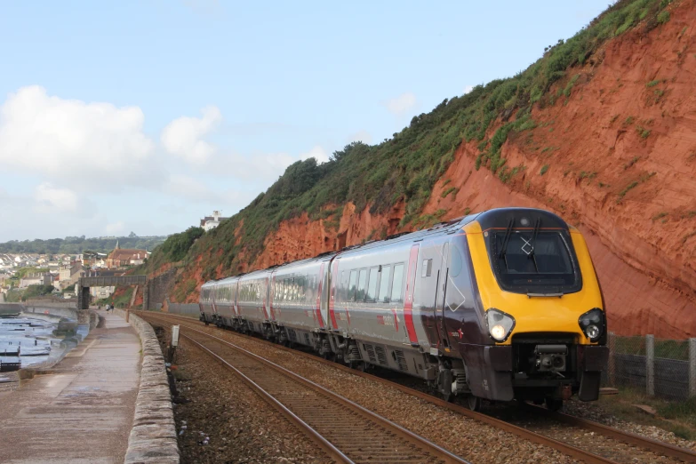 a train travelling through a country side next to a wall