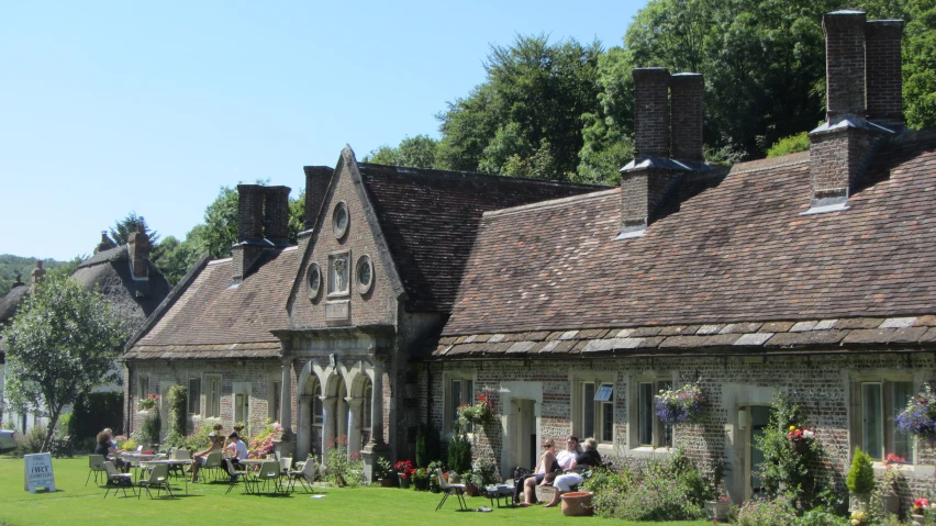 a building in the daytime with people sitting on the lawn and walking