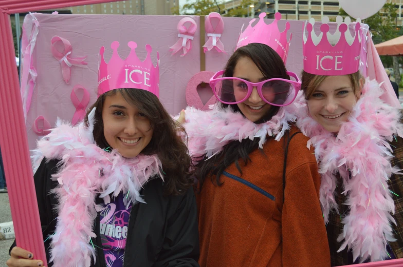 two girls in pink with pink tiaras on and a sign behind them