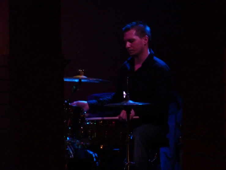 a man is playing drums in the dark