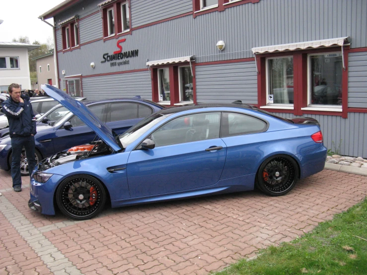 a blue car with a hood open sitting in front of a house