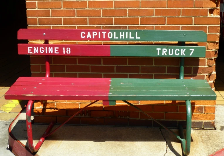 a bench sitting by a brick building with green and red painted