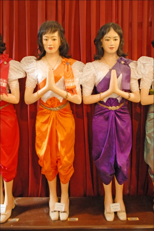 three mannequins with short skirts and white shoes with white dress holding small vases