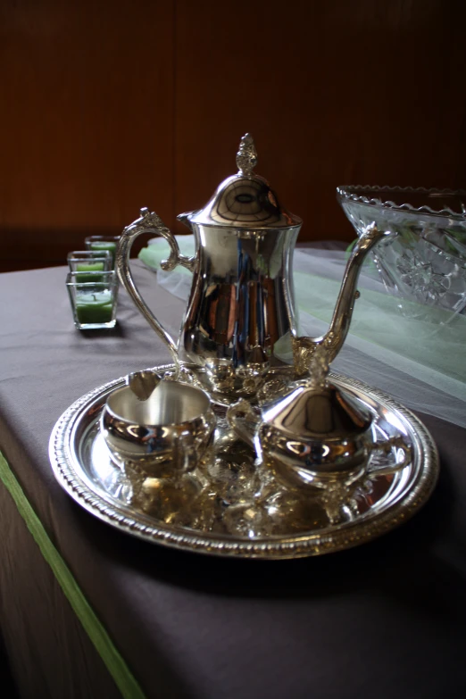 silver tea set sitting on a tray on top of a table