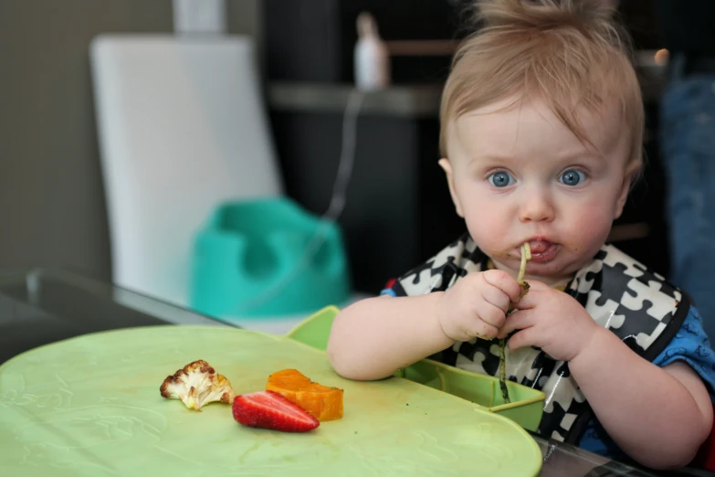 a  sits at a table and eats a piece of broccoli