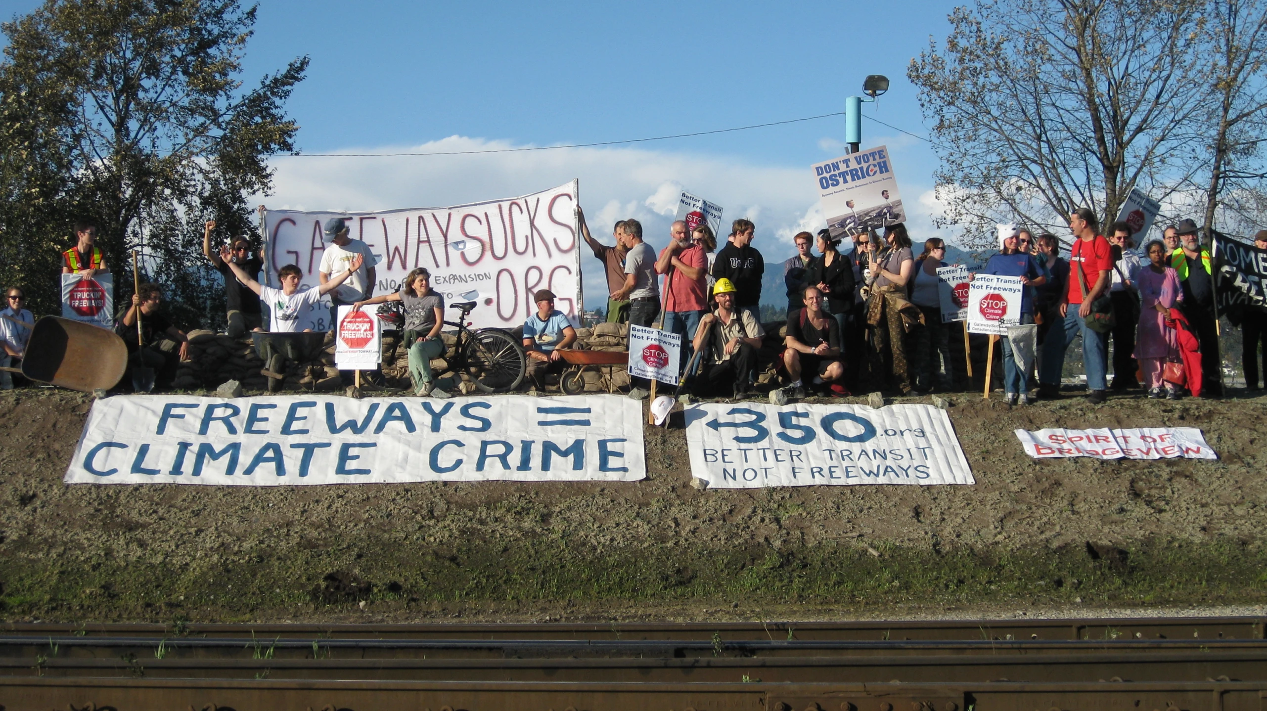 protestors stand in a field holding signs