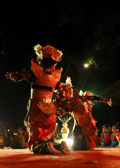 people dressed in costumes perform at night festival