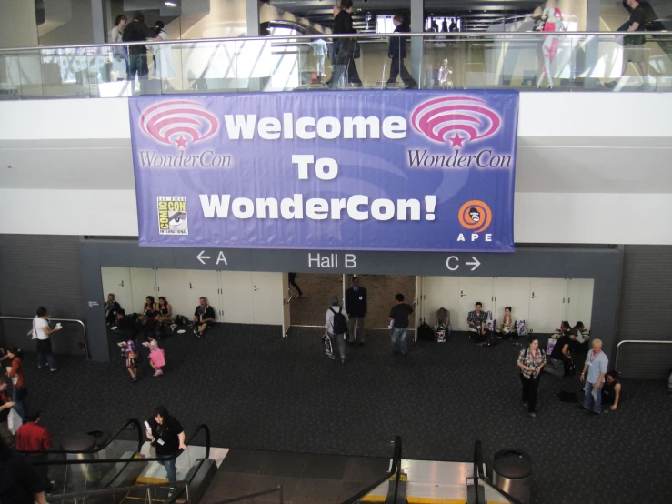 a sign with the words wonderlandcon is surrounded by a crowd of people