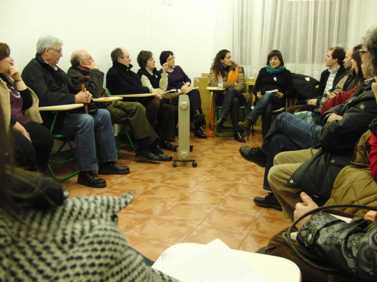 people gathered in a meeting with long tables on each side of the room