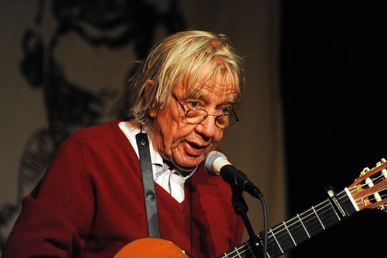 an older man with glasses is playing a guitar