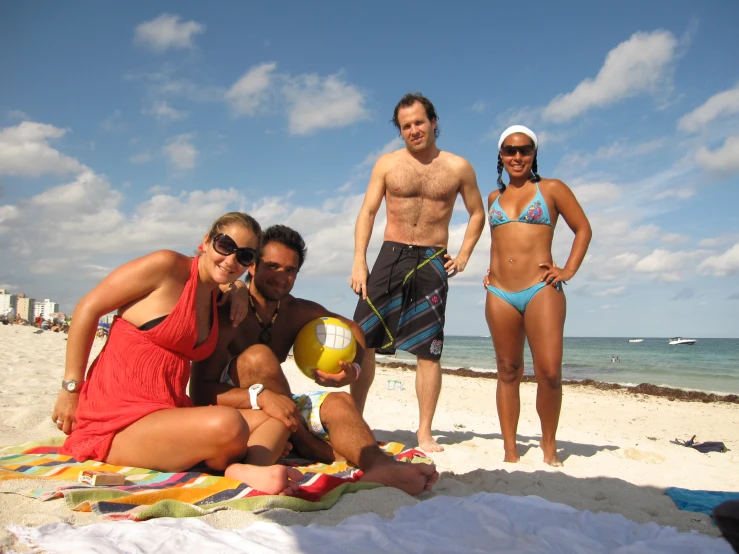 three people that are on the beach with some volleyball balls