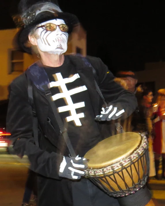 person in costume holding drum with one foot in front of him