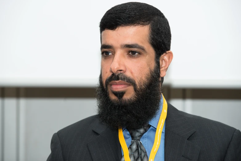 a bearded man with a yellow necklace and suit coat