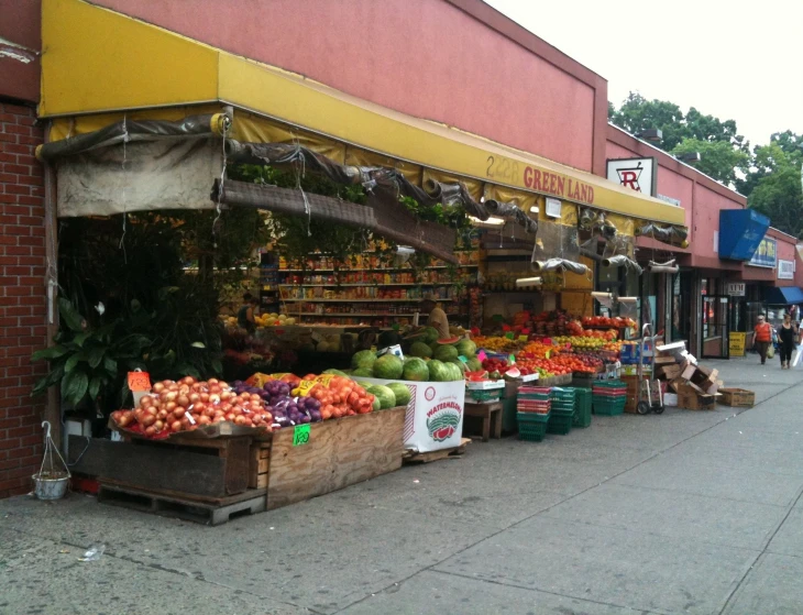 an outdoor fruit and vegetable stand on the sidewalk