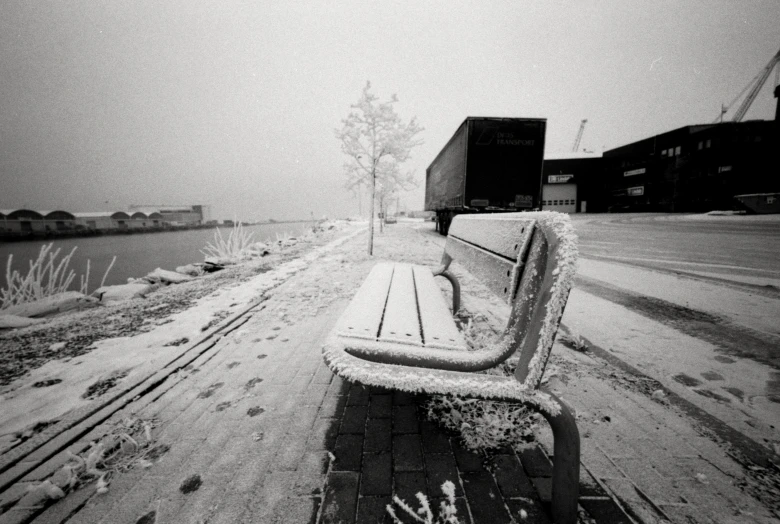 snow covered park bench sitting on the side of a road