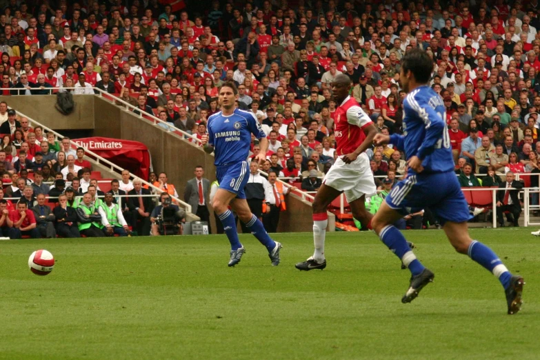 two soccer players, one chasing for the ball