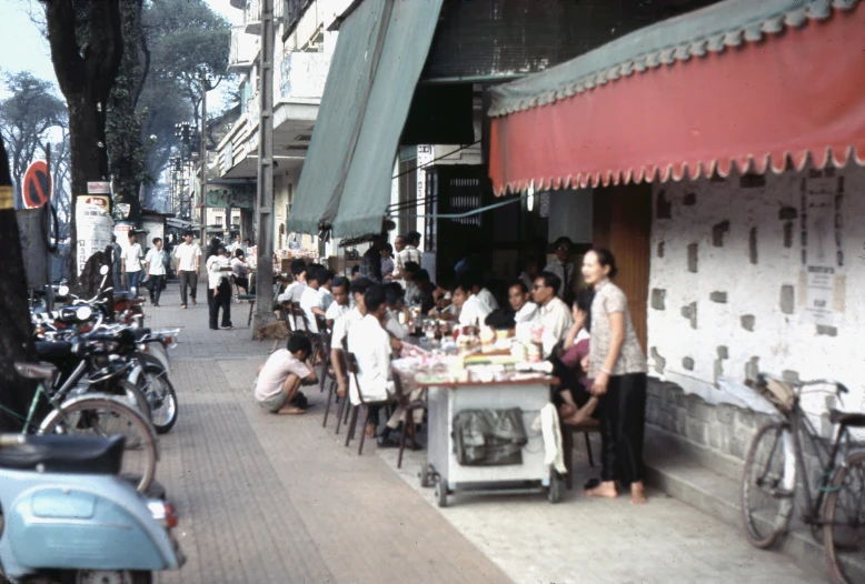 a group of people sitting at tables on a city street