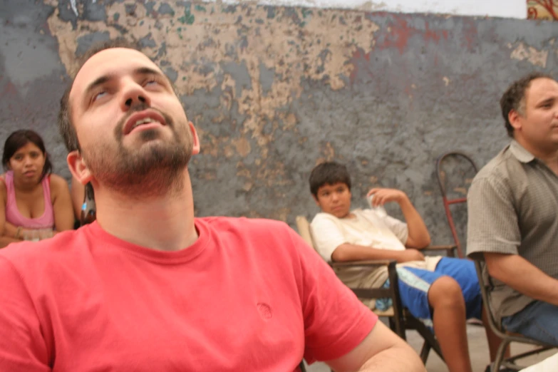 a man looking up in the air as other people sit around him