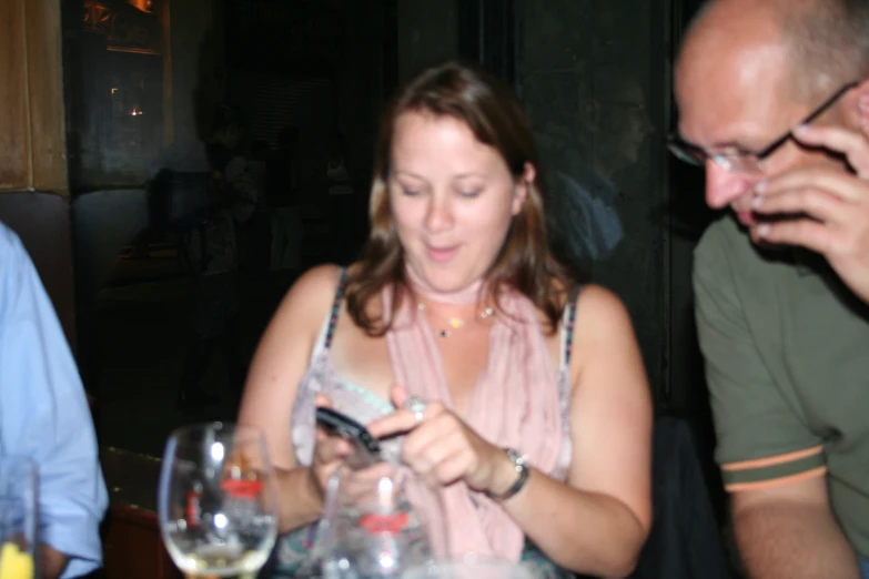 a woman looking at her phone while sitting at a table