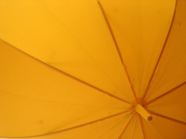 a yellow umbrella that is open with the light reflected off of it