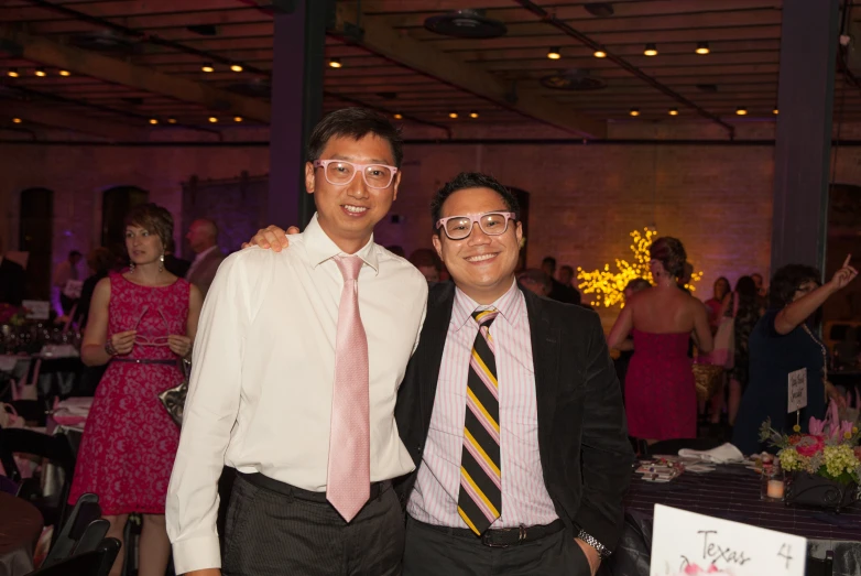 two men standing next to each other at a party