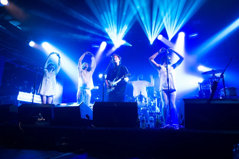 four people are singing on stage while two others are standing up