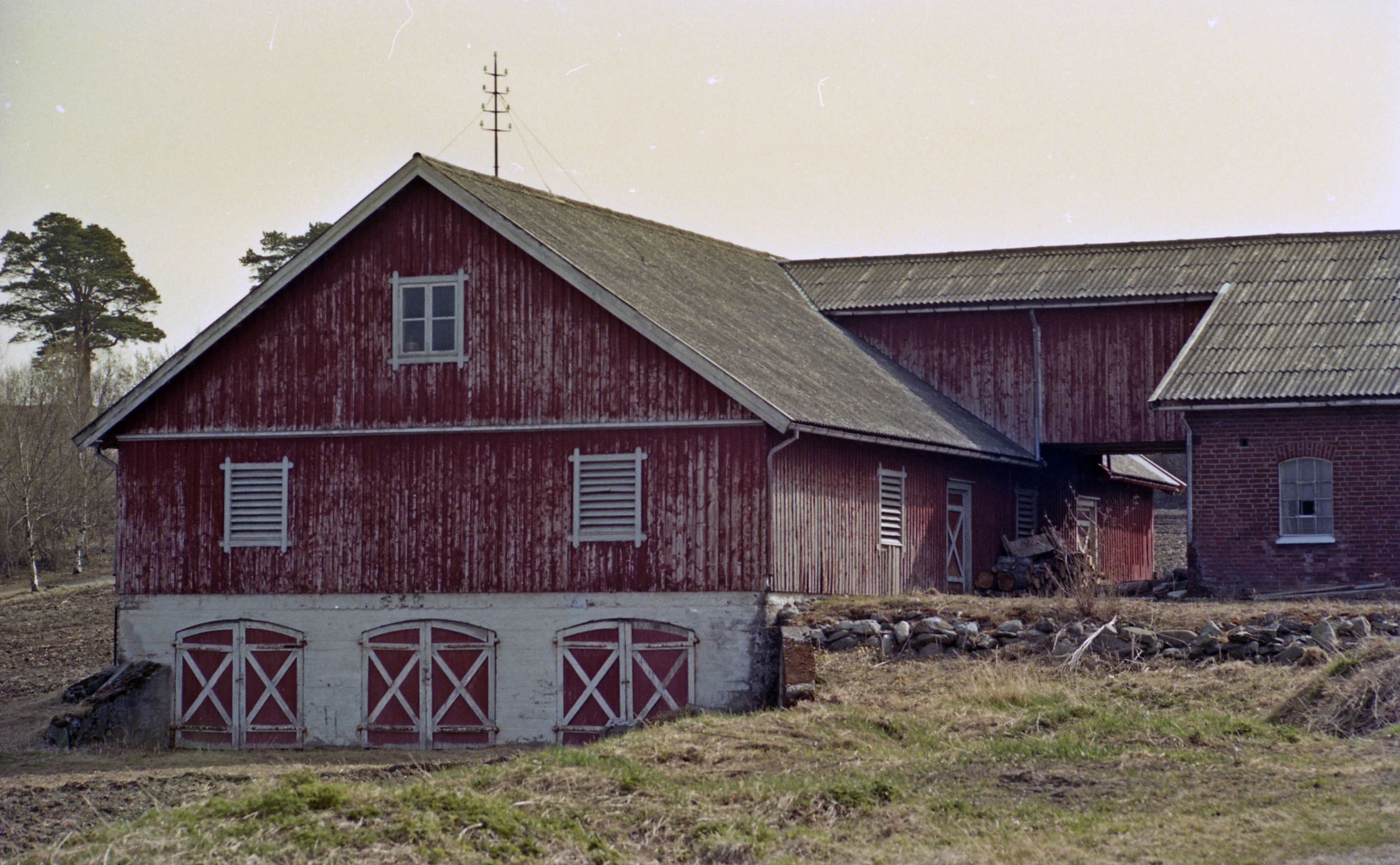 red barn with two horses grazing in the yard