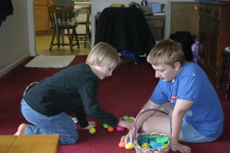 two boys are playing with plastic eggs in the room