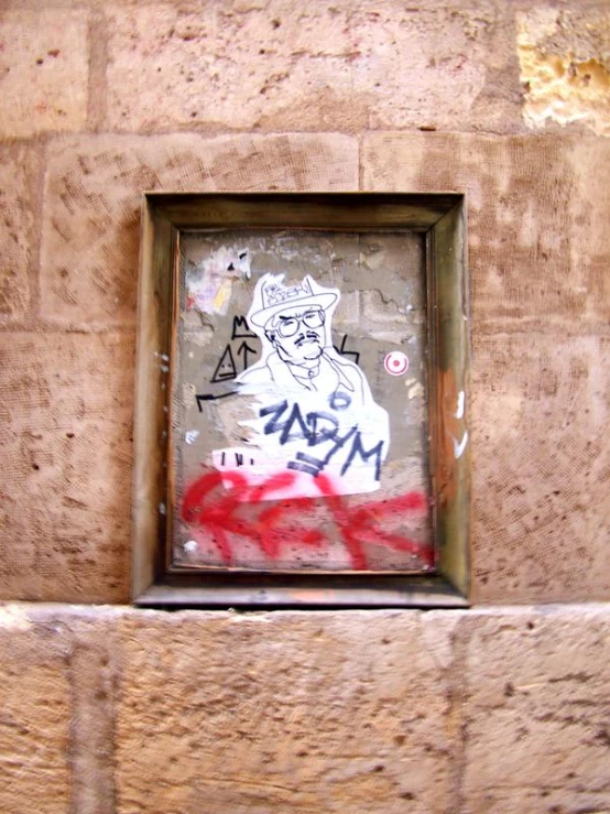 a square metal frame mounted to a wall displaying graffiti