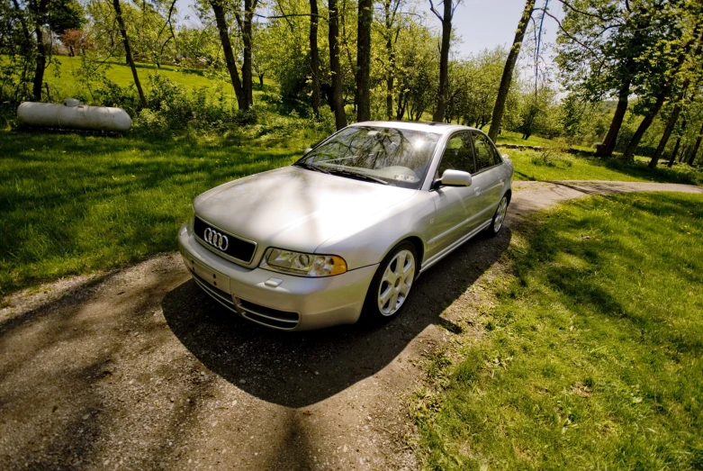 silver car parked on a small gravel road in a forest