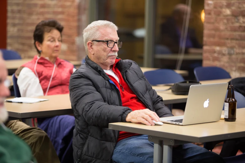 two people sit at tables with laptops