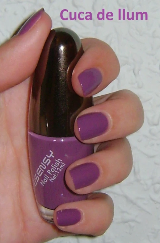 a person holding up a purple mani and purple nail polish