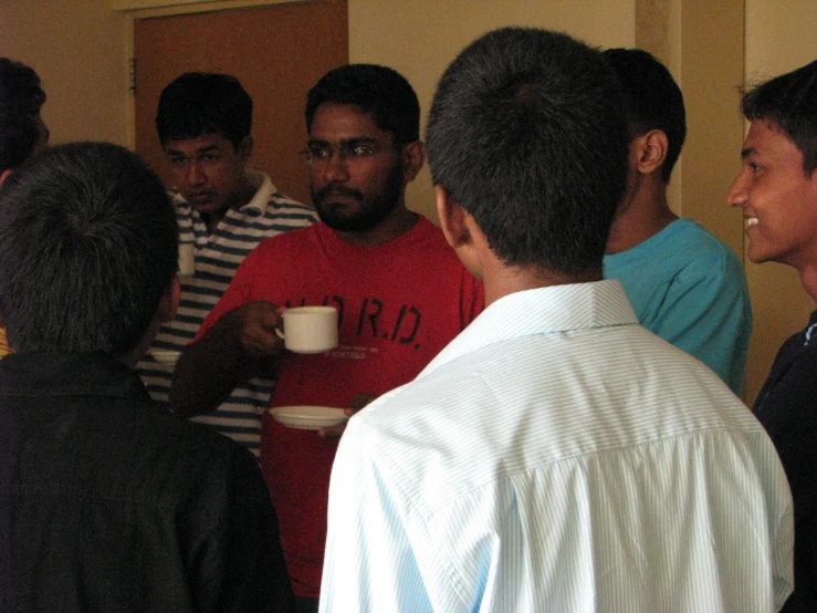 people stand talking with each other and drinking from cups