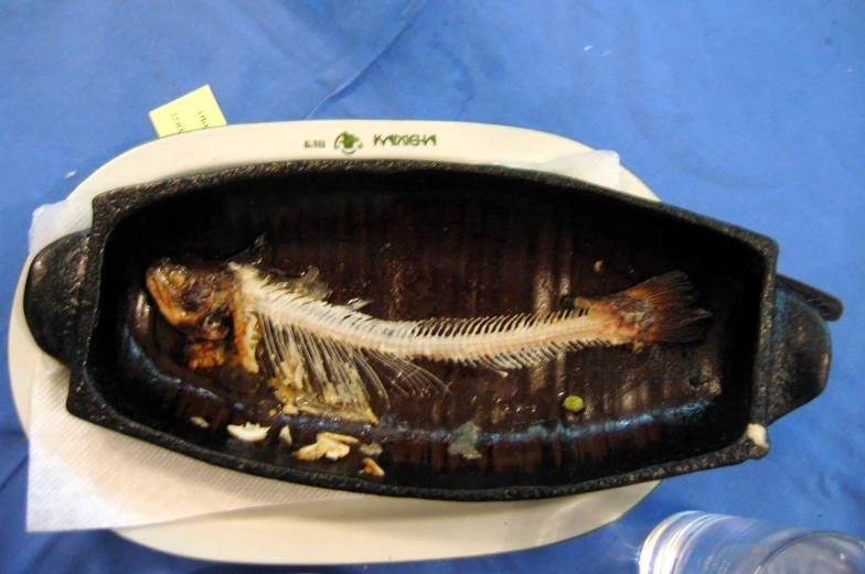 a dish on a blue cloth containing fish bones