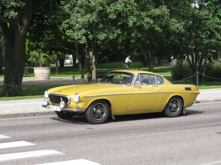 yellow classic car in the street of a small city