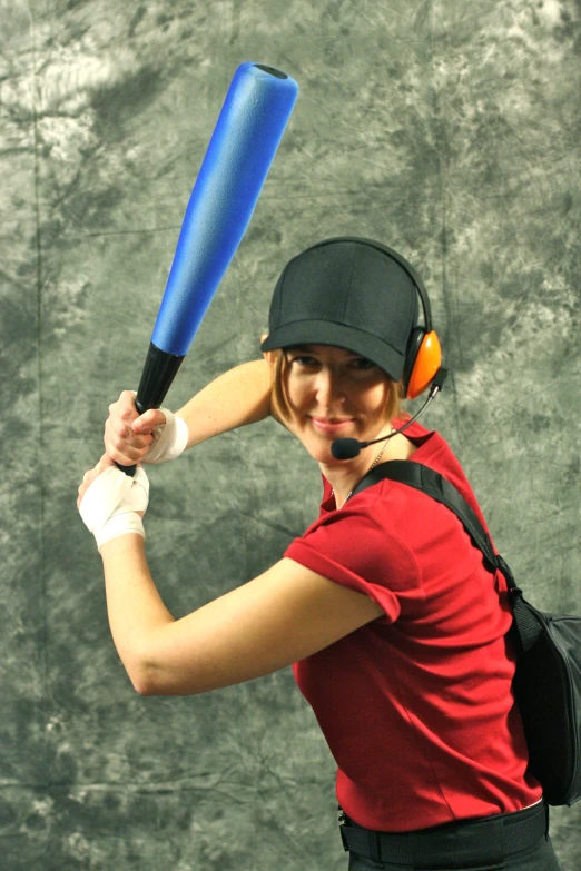 a smiling lady poses with a baseball bat