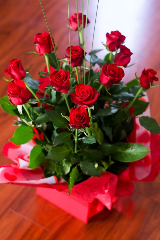 red flowers in a small pink box on a wooden table