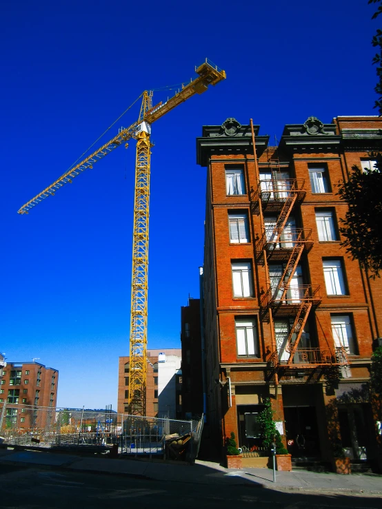 a large crane stands near a tall building