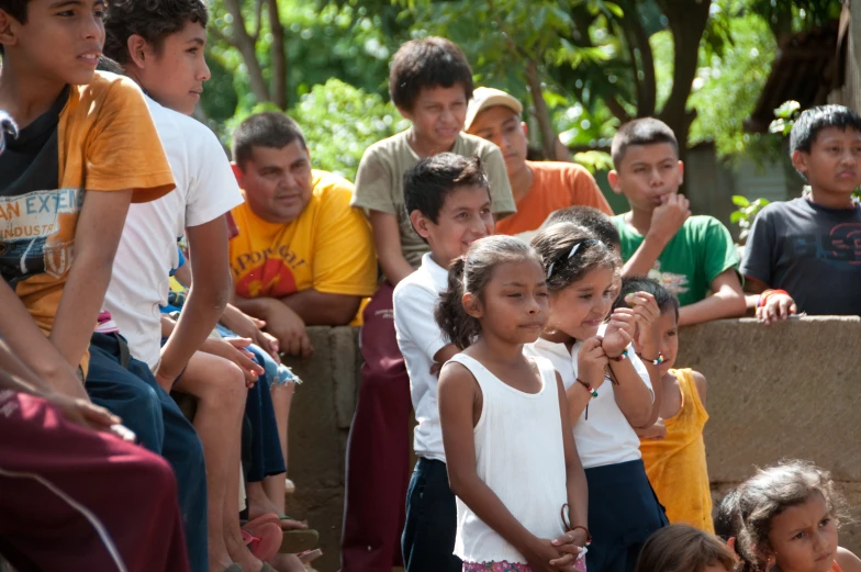 small children in front of crowd sitting on a bench