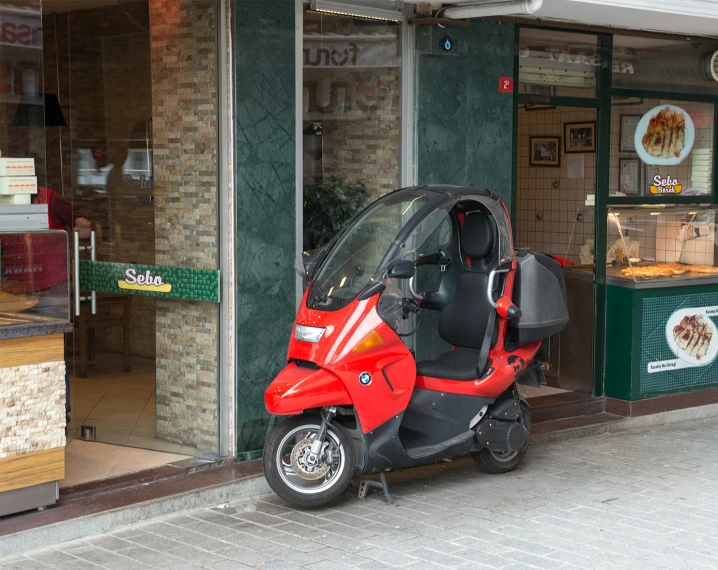 a motor scooter sits parked in front of an italian bakery