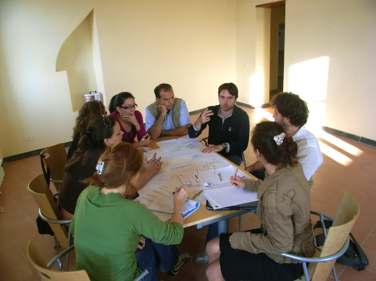 four men and one woman are around a table