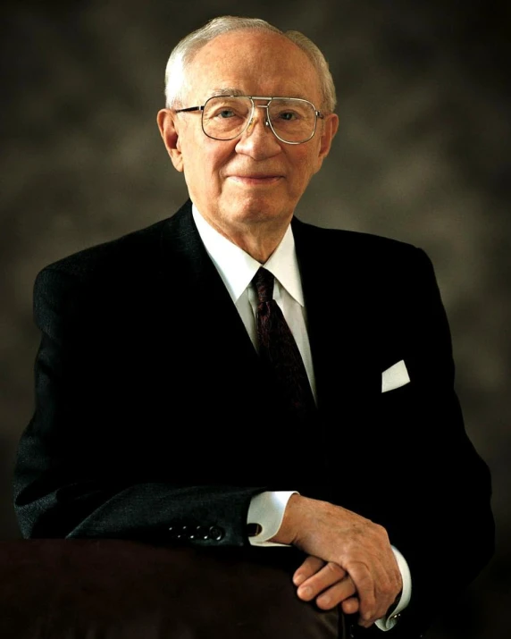 an older gentleman in suit sitting down for his po