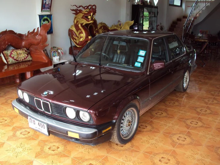 a brown bmw car in a room with tiled floors